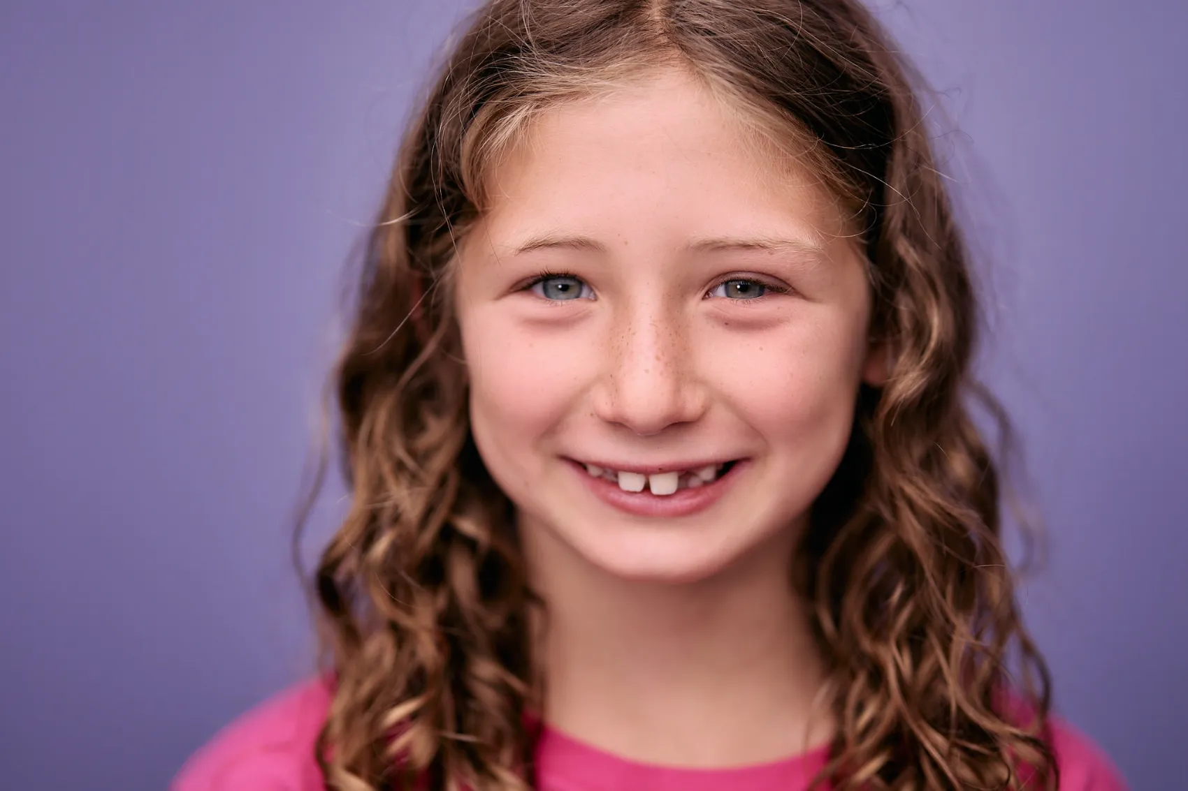 Girl with curly hair on a lilac backdrop, kids headshot photographer in Los Angeles